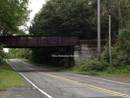 The steel girder railroad bridge that overpasses the roadway West Park Avenue extension.