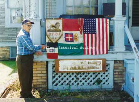 Michael Patrone points to historical memorabilia hanging on the front railing of his Historical Research Center at 242 Langley Street.