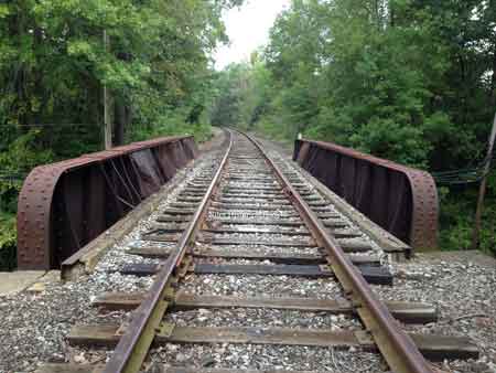 The steel girder railroad bridge that overpasses the roadway.
