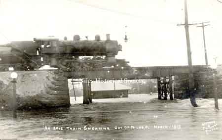 An Erie Train sneaking out of Niles, Ohio across the bridge with Church Street flooded.