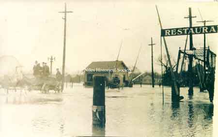 Horse-drawn wagon crossing railroad tracks which are underwater.