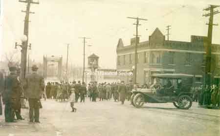 View of the intersection of Water and Main Street showing the crowd in front of the Manhattan Hotel.