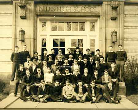 group of male students in front of main high school entrance.