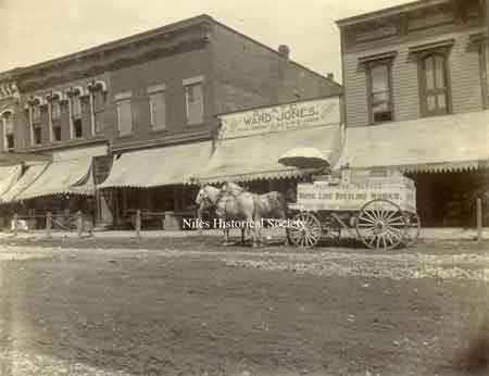 Horse and wagon, White Line Bottle Works on Wagon parked in front of the store of Ward Jones "Slate, Job work, Roofing , Tin, Iron" on store front.