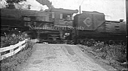 Steam locomotive and tender of the Erie Rail Road as it crosses over County Line Road in Mineral Ridge.