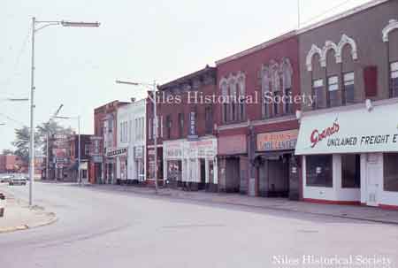 Looking north from the curve on East State Street. Grand's Unclaimed Freight, Bahm's Shoe Center, Gerke Radio & Television, Joe Antenucci Plumbing, Antique Shop, Valsi Cleaners, Lou Carbone Plumbing, and Fusco Dry Cleaners. All these buildings were demolished during urban renewal.
